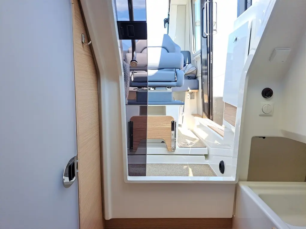 Interior view of a modern vessel featuring a doorway, seating area, and natural light streaming through the window.